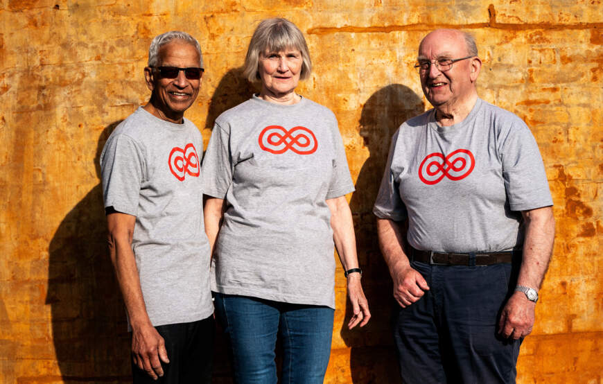 Tre frivillige står sammen i t-shirts fra Kræftens Bekæmpelse